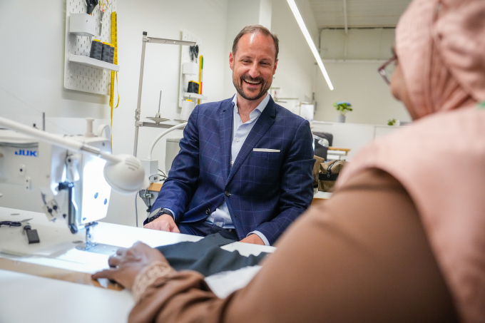 Kronprinsen fikk prøve symaskin og var med på å sy en toalettmappe i systuen i Slemmestad. Foto: Beate Oma Dahle / NTB