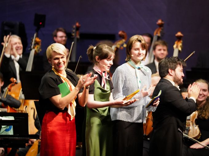 Konferansier Sigrid Bonde Tusvik og ungdomsambassadørane Inger-Eline Katla Botilsrud og Signe Stensaker fekk publikum med på fellessong og filmmusikk-gjettelek. Aage Richard Meyer er dirigent. Foto: Liv Anette Luane, Det kongelege hoffet