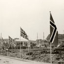 Kong Haakon ønsket å se ødeleggelsene og gjenreisningsarbeidet. I 1946 reiste han langs kysten av Finnmark med jageren Stord. Ødeleggelsene var enorme. Her er det Vardø som ønsker Kongen velkommen. Fotograf ukjent, De kongelige samlinger.