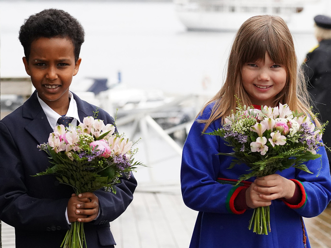 Saimon Okobalidet (8) ja Mary Loise Renfjell (8) geigiiga liđiid Gonagassii ja Dronnegii go soai lávkiiga gáddái. Sátnejođiheaddji Ivan Haugland ja politiijameaešttir Heidi Kløkstad sávaiga buresboahtima. Govven: Liv Anette Luane, Gonagaslaš hoavva. 