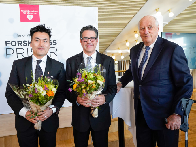 Kong Harald saman med vinnarane av Nasjonalforeningens forskingsprisar, Evandro Fei Fang og Dan Atar. Foto: Lise Åserud / NTB