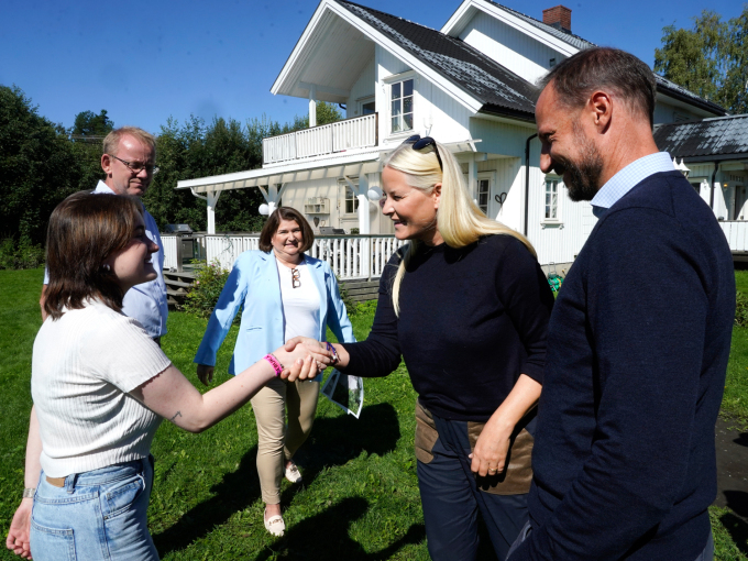 Kronprinsparet hilser på Vegard Rebne, Gunn Helen Skogen Rebne og datteren Mari som fikk Lenaelva tett på husveggen. Foto: Terje Pedersen / NTB